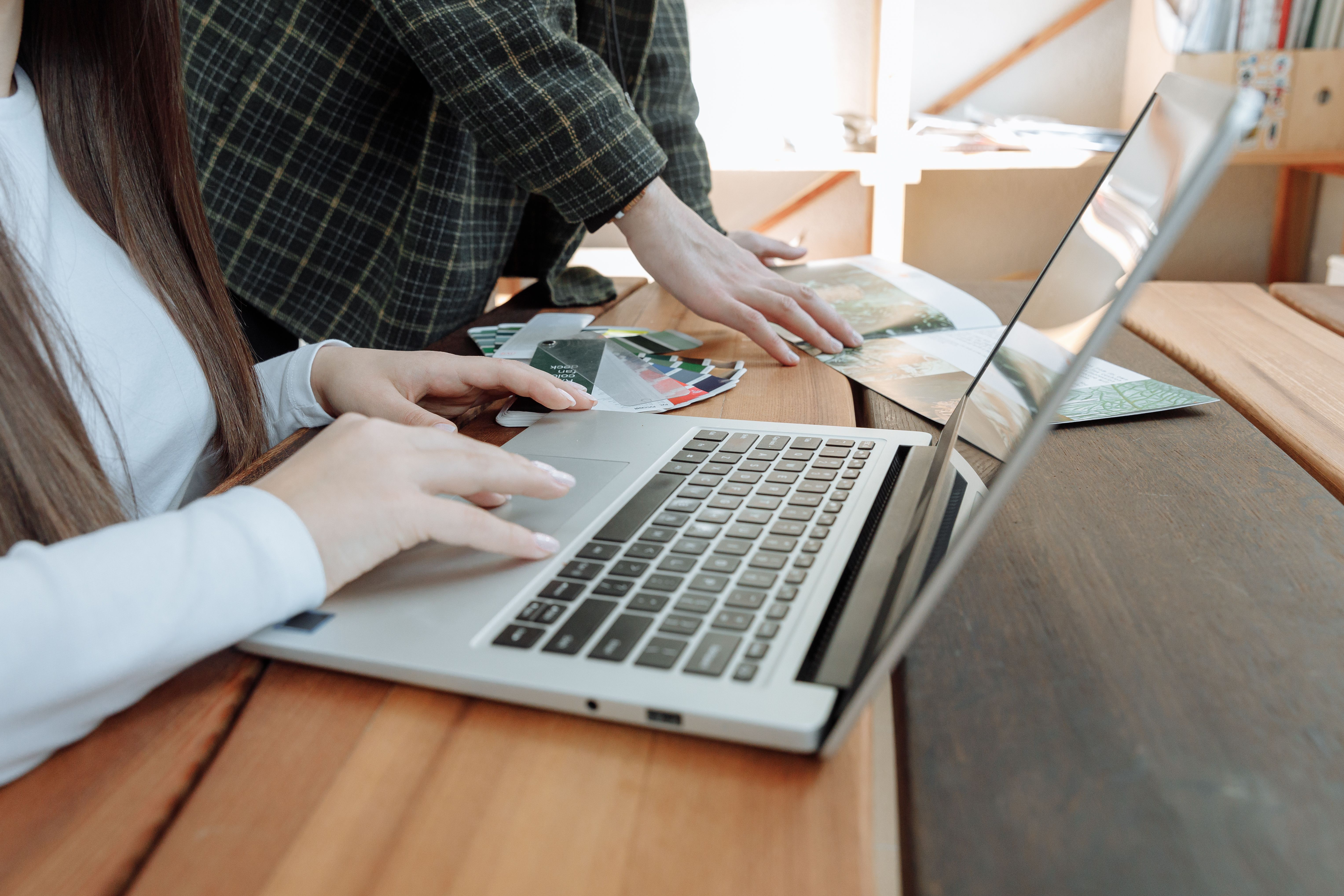 Two colleagues reviewing work together on a laptop at a shared desk